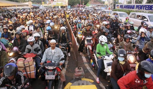 People on motorcycles form a long queue for boarding a ferry boat for home at Gilimanuk port, west Bali, Indonesia