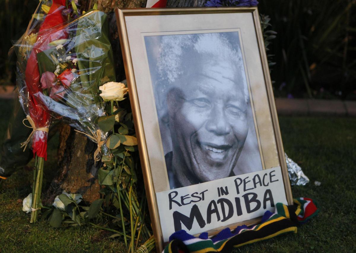 A framed portrait of former president Nelson Mandela and flowers are placed outside Mandela's Johannesburg home Friday, Dec. 6, 2013