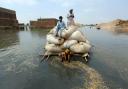 Flood victims use a makeshift barge to carry hay for cattle in Jaffarabad, a district of Pakistan's southwestern Baluchistan province, in September 2022