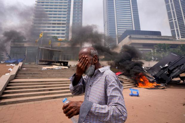 A Sri Lankan man reacts to tear gas as he walks past the vandalised site of anti-government protests outside the President’s office in Colombo, Sri Lanka, on Monday May 9 2022