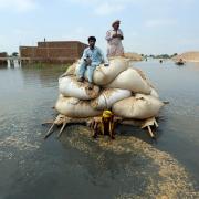 Flood victims use a makeshift barge to carry hay for cattle in Jaffarabad, a district of Pakistan's southwestern Baluchistan province, in September 2022