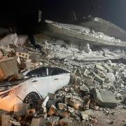 A car is seen under the wreckage of a collapsed building, in Azmarin town, in Idlib province, northern Syria